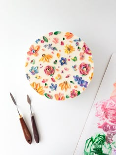 a plate with flowers painted on it next to paintbrushes