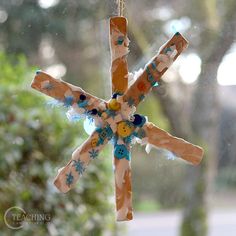 an ornament made out of clothes pins hanging from a string in front of a window