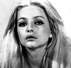 a black and white photo of a woman with long blonde hair looking at the camera