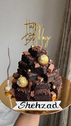 a cake that is sitting on top of a gold plate with a happy birthday sign