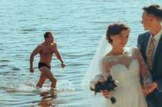 a bride and groom walking into the water