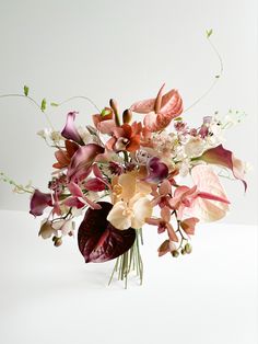 a vase filled with lots of flowers on top of a white tablecloth covered floor