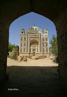 an archway leading to a large building in the middle of nowhere