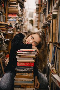 a woman sitting on the floor in front of a stack of books