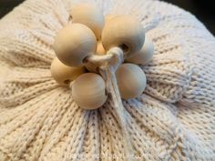 a white knitted beanie with wooden beads on it's side and the top knoted up