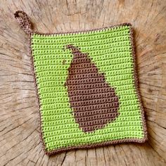 a green and brown crocheted square with an acorn on it