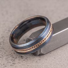 two wedding rings sitting next to each other on top of a metal block with a knife in the background