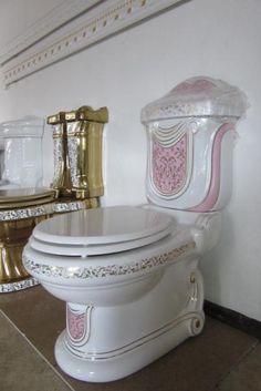 a white toilet with pink and gold decorations on it