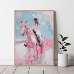 a painting of a girl riding a horse in pink and blue colors on a white wall next to a potted plant