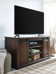 a flat screen tv sitting on top of a wooden entertainment center in a living room