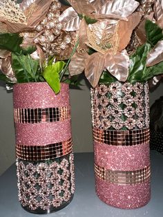 two vases with flowers in them sitting on a table next to each other,