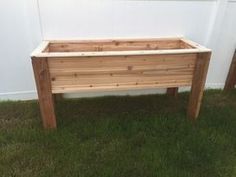 two wooden planters sitting in the grass near a white wall and green grass on the ground