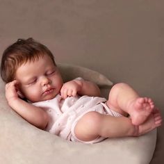 a baby is sleeping in a white bowl