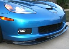 the front end of a blue sports car parked in a driveway next to a house