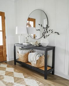 a console table with baskets and a mirror on it in a white living room area