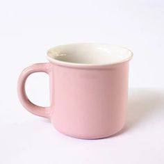 a pink coffee cup sitting on top of a white table