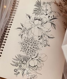 an open notebook with flowers and butterflies drawn on it next to a plant, pencil drawing