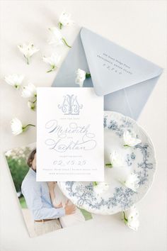 the wedding stationery is laid out on top of an envelope, with white flowers