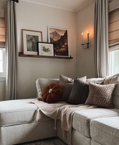 a couch with pillows and pictures on the wall in front of it's windows