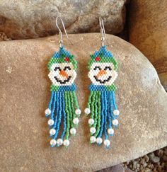 a pair of beaded bird earrings sitting on top of a rock