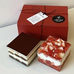 two boxes with strawberries and chocolate cake inside one box has a tag on it