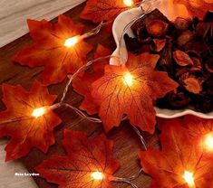 lighted leaves are on the table next to a bowl