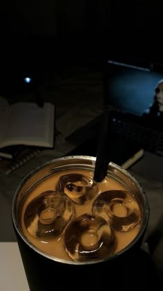 a cup filled with liquid sitting on top of a table next to a laptop computer