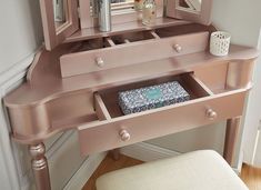 a pink vanity with drawers and mirror on it