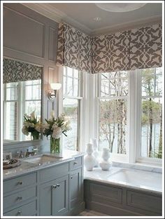 a bath room with a large window next to a sink and a tub filled with flowers