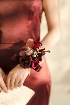 a woman in a red dress holding a book and flower bouquet with her hand on it