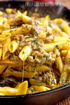 a skillet filled with pasta covered in cheese and ground beef, on top of a wooden table