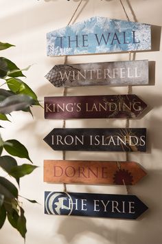 a wooden sign hanging from the side of a wall next to a potted plant