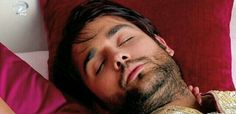 a man sleeping on top of a red pillow next to a pink pillow case with his eyes closed