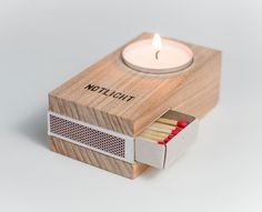 a matchbox with matches and a lit candle in it that says,'thichlott '