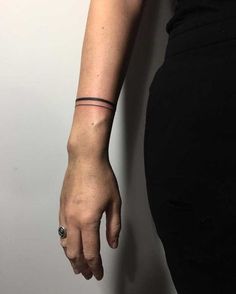 a woman's arm with a small black tattoo on her left wrist and a ring around the wrist