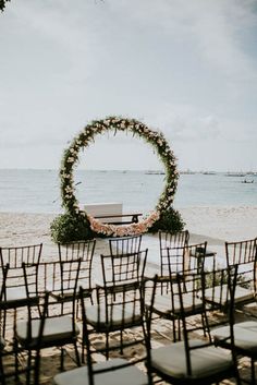 an outdoor ceremony setup with chairs and flowers on the beach