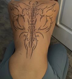 the back of a woman's body with an intricate tattoo design on her lower back