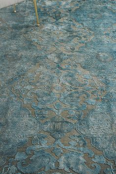 a blue rug with an intricate design on the floor in a living room or bedroom