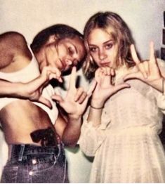 two young women standing next to each other making the peace sign with their hands and fingers