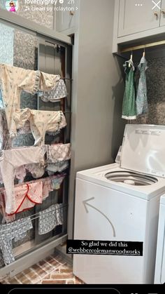 a washer and dryer sitting next to each other in a room with clothes hanging on the wall