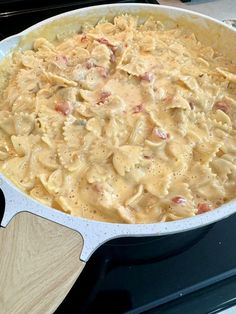 a casserole dish is sitting on the stove with a wooden spatula next to it