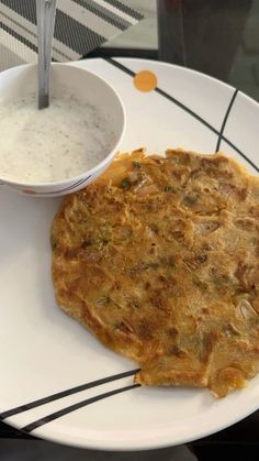 a white plate topped with an omelet next to a bowl of yogurt