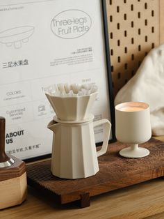 a coffee maker sitting on top of a wooden table next to a cup and saucer