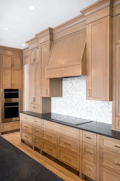 a large kitchen with wooden cabinets and black counter tops, along with white marble backsplash