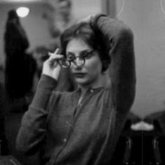 black and white photograph of a woman with glasses on her head, sitting in a chair