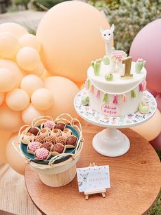 a table topped with a cake and lots of balloons