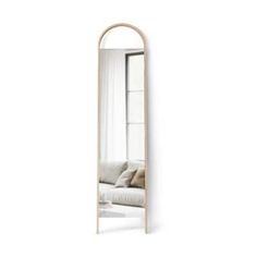 a large mirror sitting on top of a white wall next to a couch and window