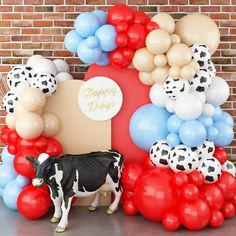 a black and white cow standing in front of balloons