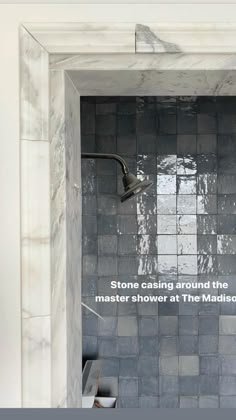 a bathroom with a shower head and tiled walls that reads stone casing around the master shower at the madison