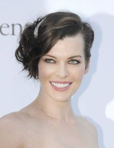 a woman in a strapless dress smiling at the camera with her hair pulled back